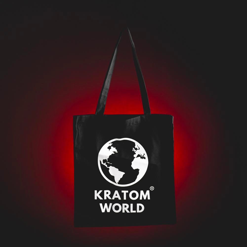 Платнена пазарска чанта Kratom World, представена в продуктов кадър с Green Maeng Da kratom.