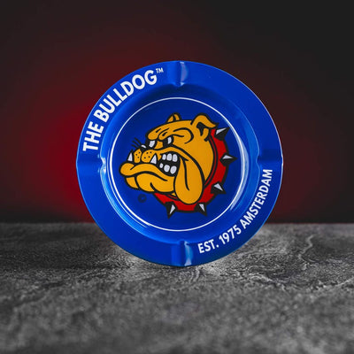 Син Bulldog пепелник Kratom World, представен в продуктов кадър като аксесоар за CBD и билкови продукти.